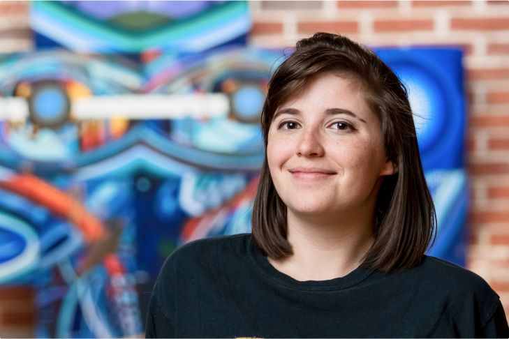Student at CBU poses in front of artwork