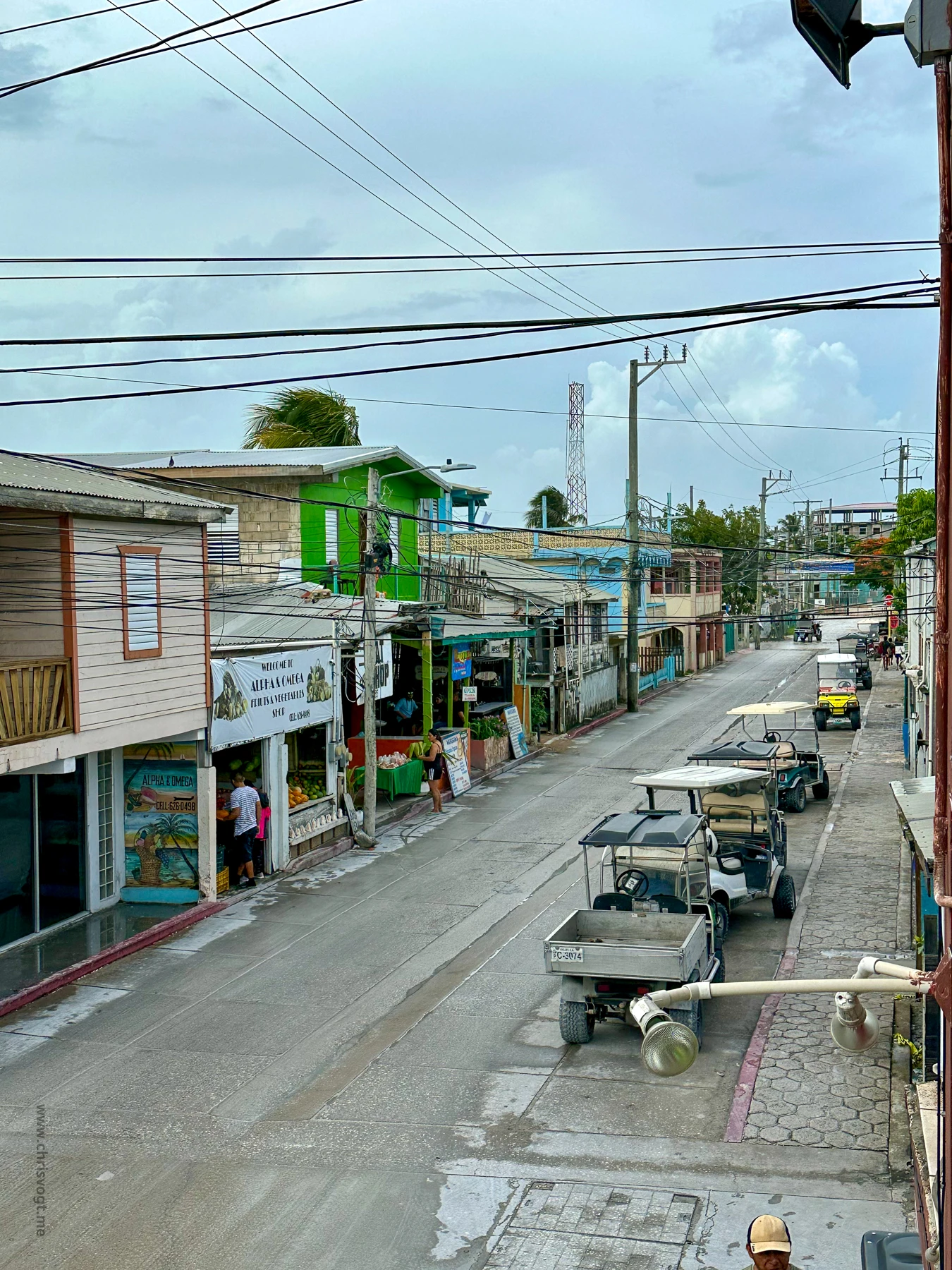 Looking down the street in San Pedro, Belize. Golf carts park along the side of the road.
