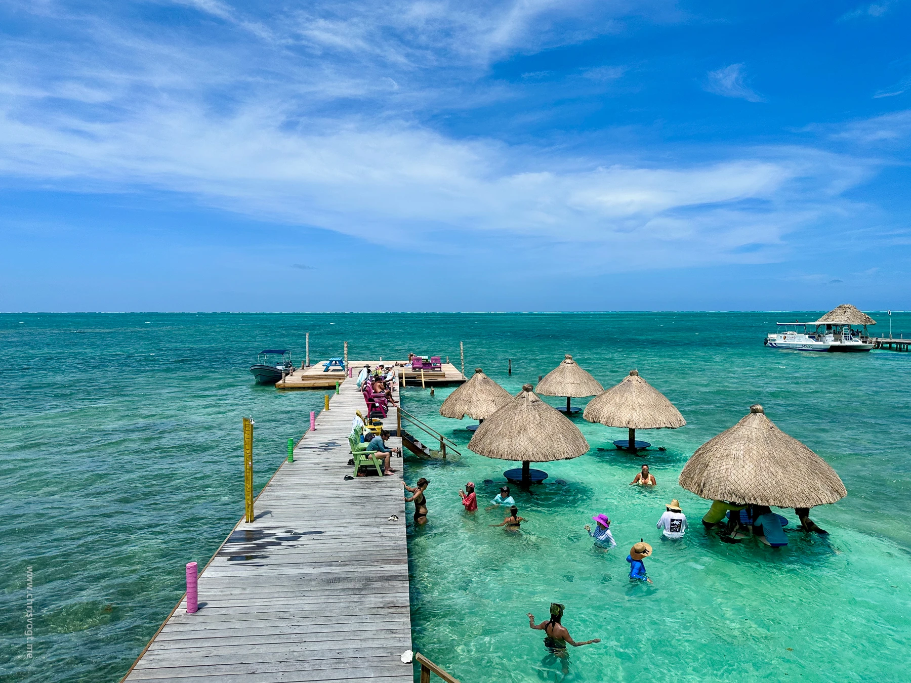 People swimming and lounging at the Sip n' Dip in Caye Caulker, Belize. Where you sit in chairs on the water and drink cocktails.