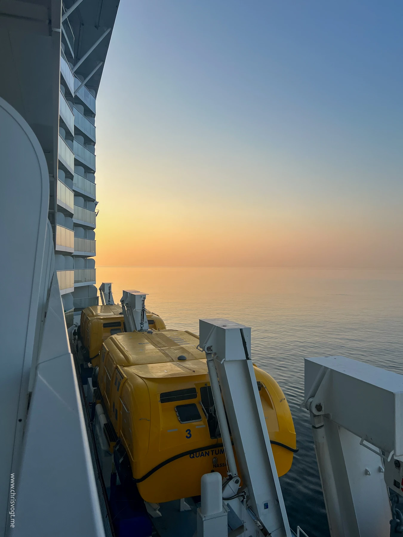 Looking out the balcony of my stateroom as the sun sets over yellow-painted lifeboats