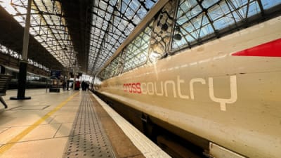 Wide angle view of a train operated by Cross Country rail alongside a platform at a railway station..png