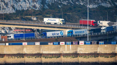 Trucks queue to enter the Port of Dover and a cross channel ferry to France..png