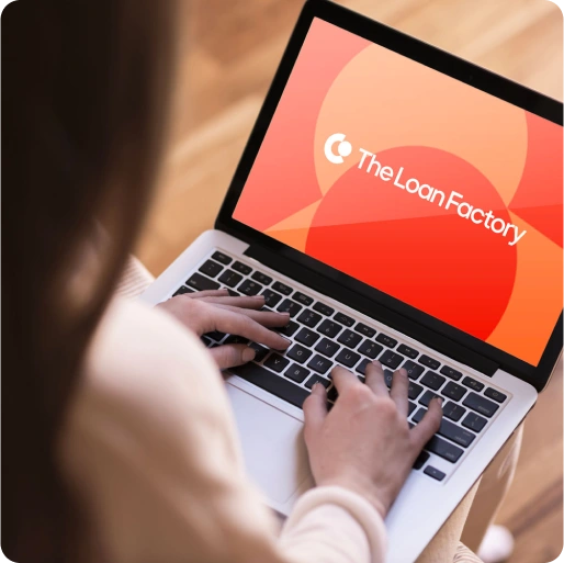 a woman working on a laptop with the LoanFactory logo in the background of the screen