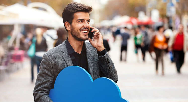 Mann, der am Telefonieren ist und eine Wolke in der Hand hält, die für Cloud-Telefonie stehen soll