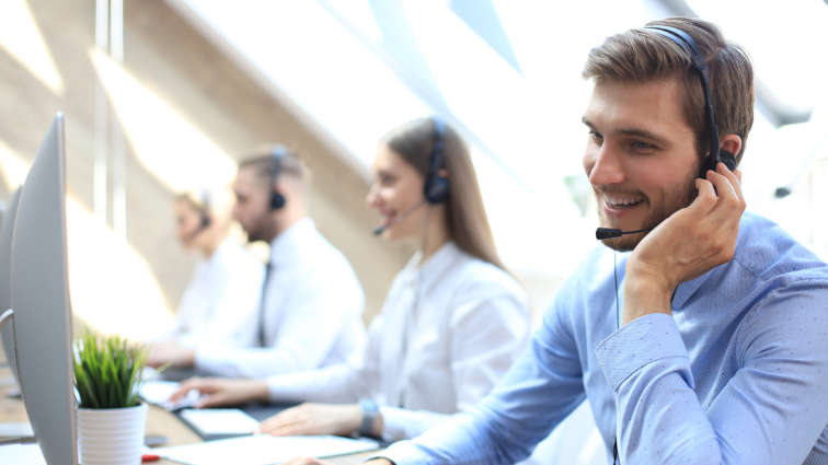 Lächelnder Customer Support Mitarbeiter bei der Arbeit im Call-Center