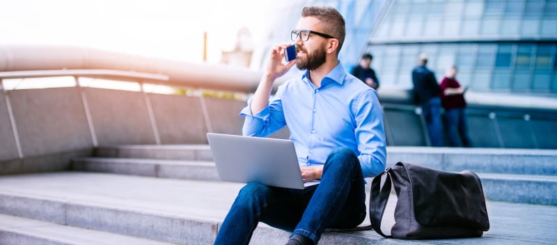 Mann telefoniert auf einer Geschäftsreise über eine Telefonie Software auf seinem Smartphone