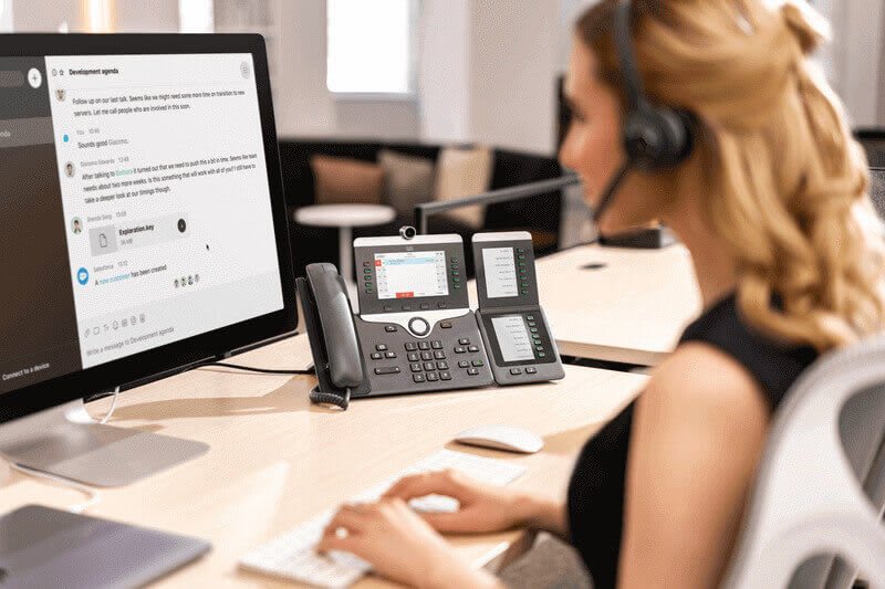 Eine Frau telefoniert am Arbeitsplatz mit der Cisco Telefonanlage