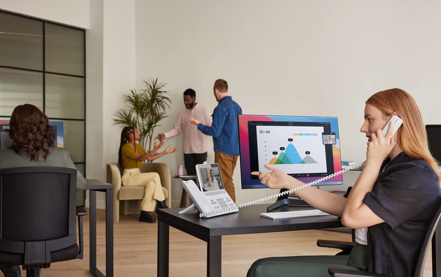 Frau im Büro telefoniert am Schreibtisch mit weißem Cisco Tischtelefon