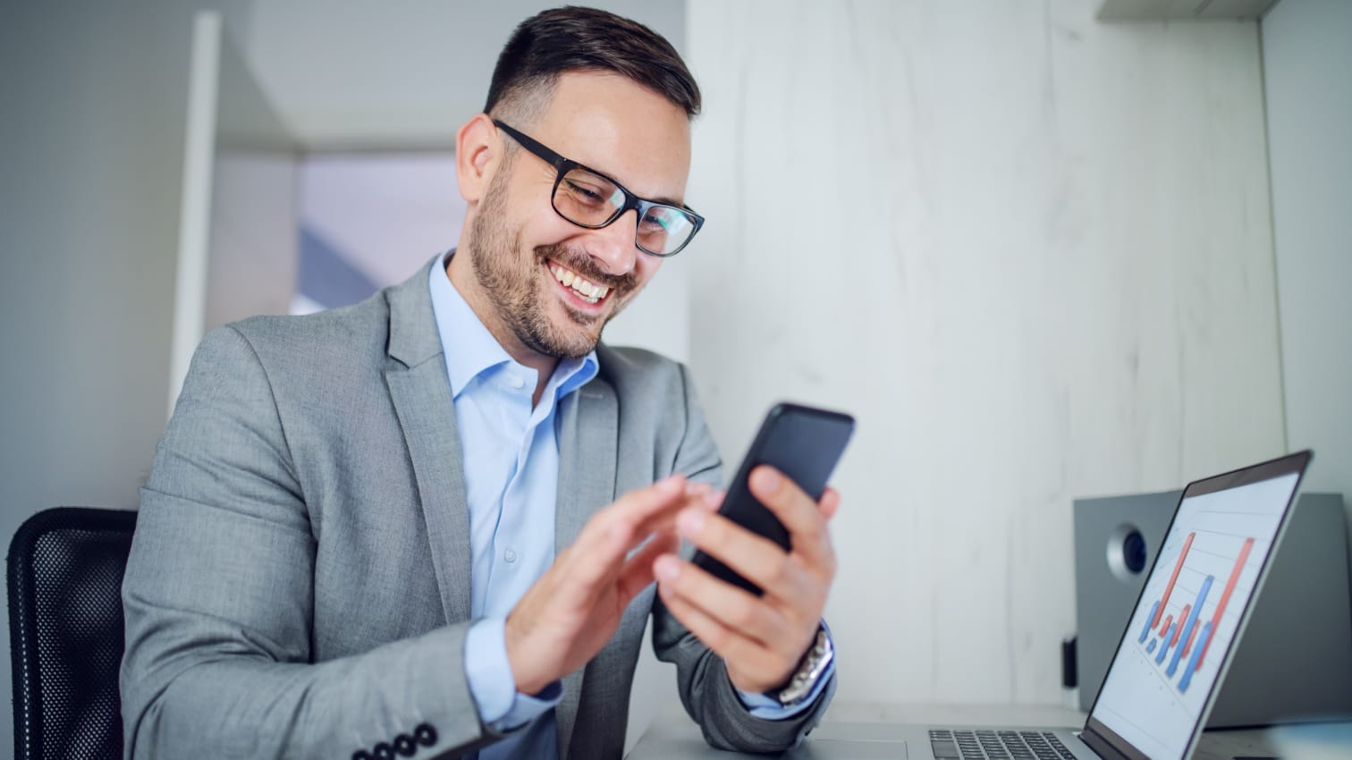 Mitarbeiter tippt am Arbeitsplatz auf seinem Diensthandy