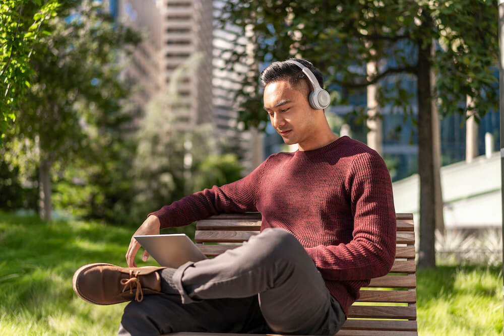 Mann, der im Park auf seinem Laptop arbeitet