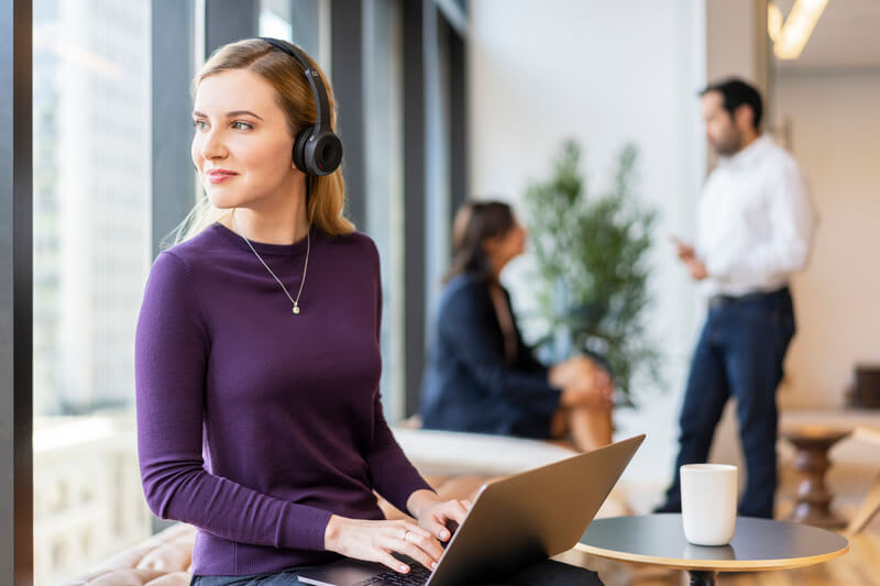 Frau arbeitet mit einem Headset am Laptop
