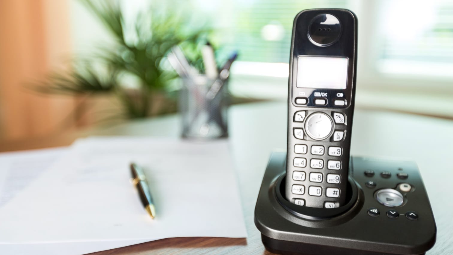 Schwarzes Dect-Telefon steht in seiner Basis auf dem Schreibtisch