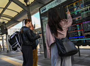 People looking at a bus sign board in Kyoto, Japan