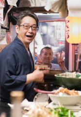 Tourists enjoying a meal with a local guide at a busy restaurant in Japan