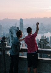 Local guide pointing out famous buildings to a tourist from a viewpoint overlooking Hong Kong
