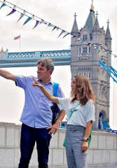 Local guide pointing out popular attractions to a tourist in London with Tower Bridge in the background