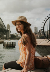 Tourist in summer clothes and a hat posing in front of Sydney Harbor Bridge