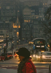 Tourists and a local guide walking along a street in Edinburgh at night