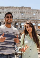 Tourist couple posing in front of the Colosseum while on a tour of Rome