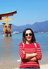 Tourist standing in front of Itsukushima Floating Torii Gate while on a tour of with a private guide in Hiroshima 