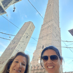 Towering Giants: A Smiling Moment Beneath Bologna's Skies
