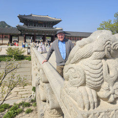 Man poses near carved stone figures at Gyeongbokgung Palace entrance.