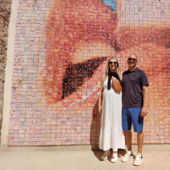 Two people stand in front of the 'El Beso' mural in Barcelona.