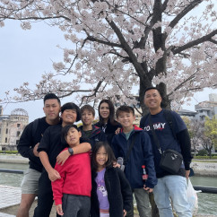Tourists gathered at Hiroshima's Peace Park with iconic dome in the background.