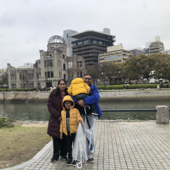 Group pictured with Hiroshima Peace Memorial and cityscape background.