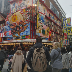 Street scene with people in front of Shinsekai district shopfront, Osaka, Japan.