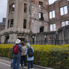 A view of the Atomic Bomb Dome in Hiroshima, Japan with visitors nearby.