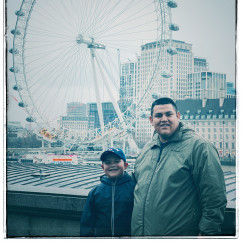 A man and child stand in front of the London Eye.