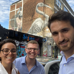 Street art featuring a large bird visible behind people on Brick Lane, London.