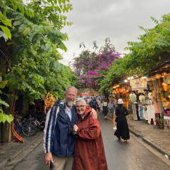 Hoi An street scene with a couple and market vendors.