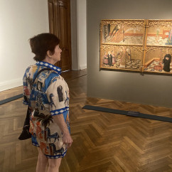 Museum visitor observing medieval artwork on display.