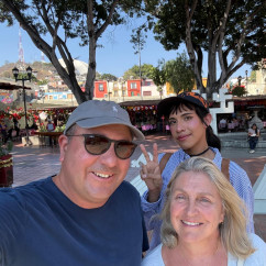 Three people posing at a Mexican square with shops in the background.