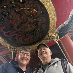 Two people standing under a large red lantern at Senso-ji Temple, Tokyo.