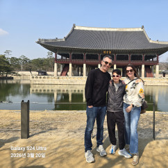 Family posing in front of Gyeonghoeru Pavilion at Gyeongbokgung Palace, Seoul.