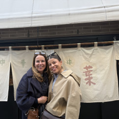Two people standing in front of a restaurant with Japanese signage.
