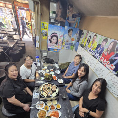 Group dining at a Korean barbecue restaurant with various dishes on the table.