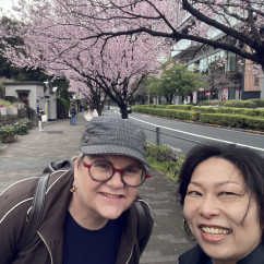 People posing on a path with blossoming cherry trees in the background.