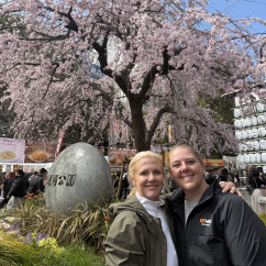 Two people pose in front of a cherry blossom tree in Tokyo.
