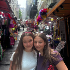 Tourists pausing for a smile amidst Hong Kong's bustling market lanes.