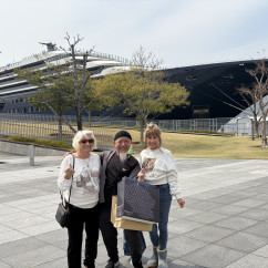 A happy trio poses by an impressive ship in Nagasaki.
