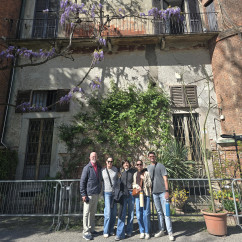 Friends pause to appreciate wisteria trailing a historic facade in Milan.