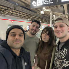 A joyful group selfie beneath bright station signs in Tokyo.