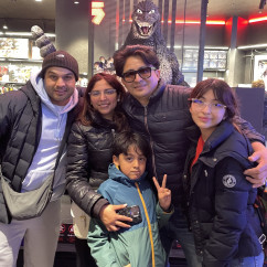 A cheerful group poses with a Godzilla figure in Tokyo.