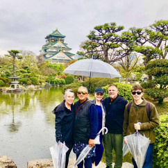 A group enjoys a rainy day stroll in Osaka's gardens.