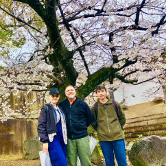 Tourists standing under cherry blossoms in full bloom, smiles all around.
