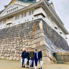 A group stands together under the grandeur of Osaka Castle.